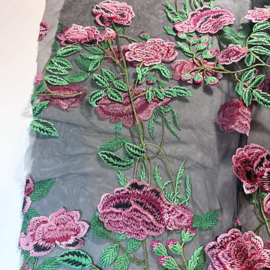 Black tulle with pink flowers and green leaves embroidered on to fabric