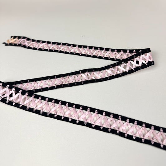 Pink criss cross trim with black border on a light beige background