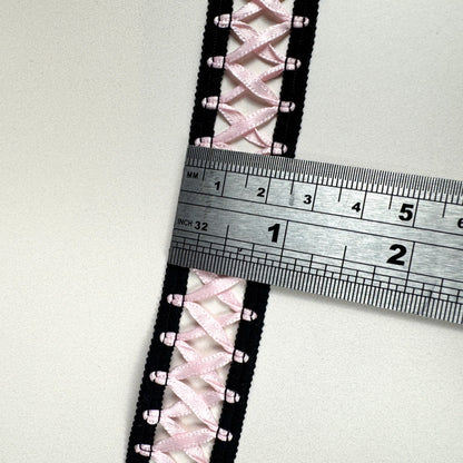 Close-up of pink laced fabric with a ruler for scale on a white background