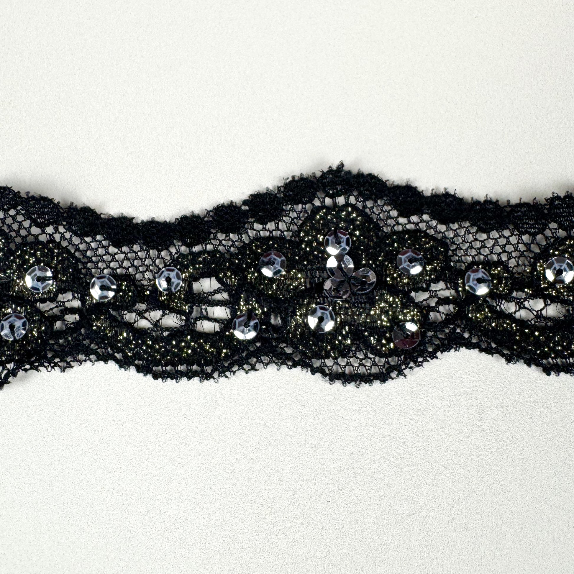 Black lace trim with embedded sequins on a white background