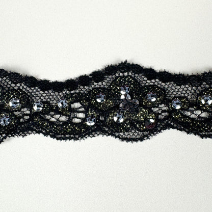 Black lace trim with embedded sequins on a white background