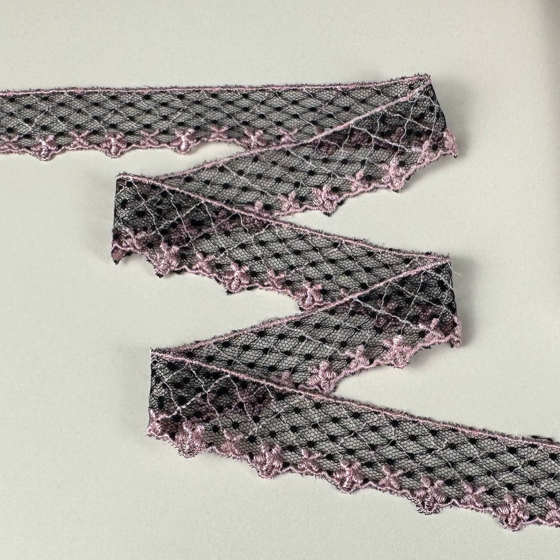 Black diamond mesh trim with pink accents on a light background